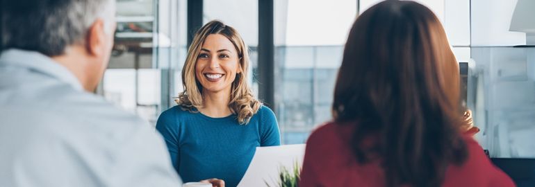 A woman engages in a discussion about counter-offers with two colleagues in a professional office environment.