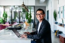 A man working at a kitchen counter smiling at the camera.