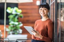 Woman holding a tablet and smiling at the camera.