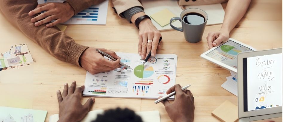 Colleagues focused on salary increment negotiations, utilising a laptop and analysing paperwork together.