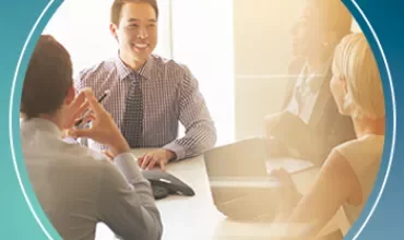 Business meeting with four people discussing around a table.