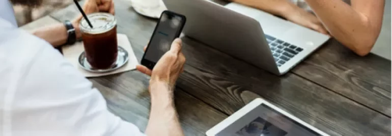 Two people working on electronic devices at an outdoor table.