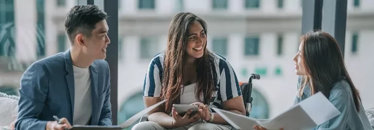 Three people having a friendly meeting in a modern office space.