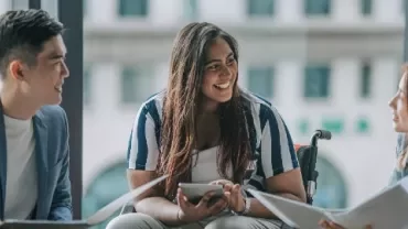 Three people having a friendly meeting in a modern office space.