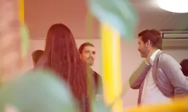 People chatting in a warmly lit room with plants.