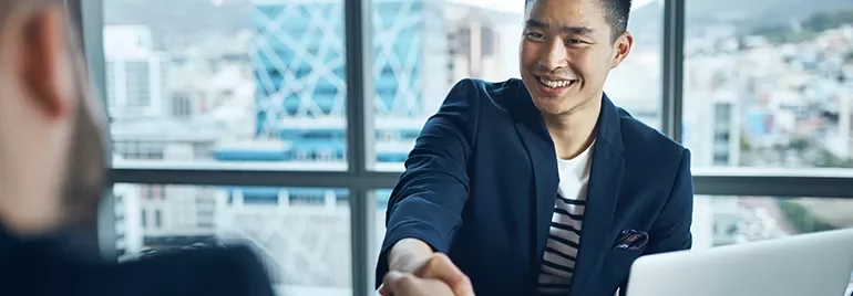 Smiling man in a blue blazer shakes hands in an office.