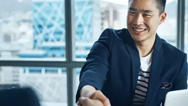 Smiling man in a blue blazer shakes hands in an office.