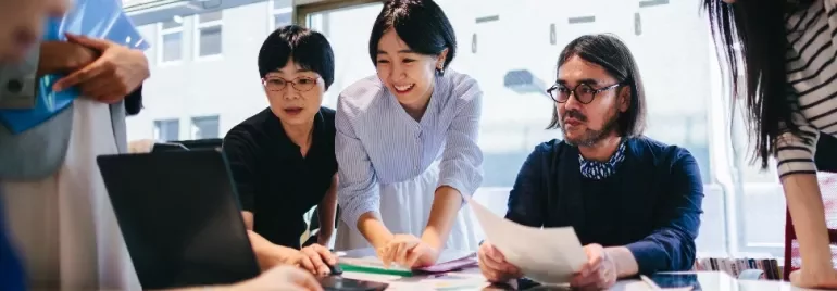 Group of people collaborating at a table in a modern office.