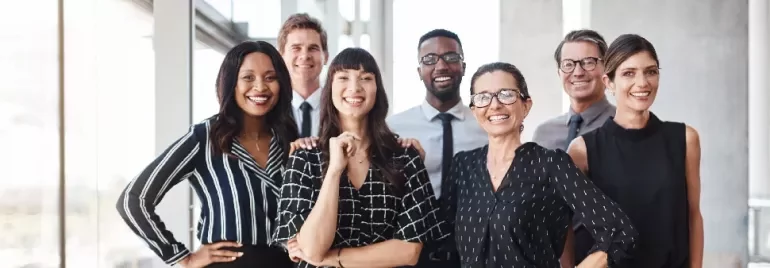 Group of diverse professionals smiling in an office setting.