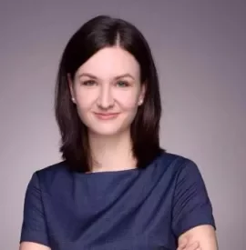 Portrait of a smiling woman with dark hair in a blue shirt.