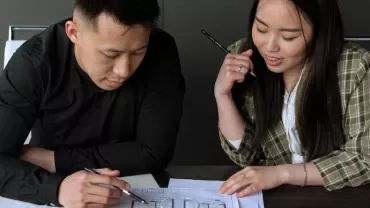 Two people discussing architectural plans at a table.
