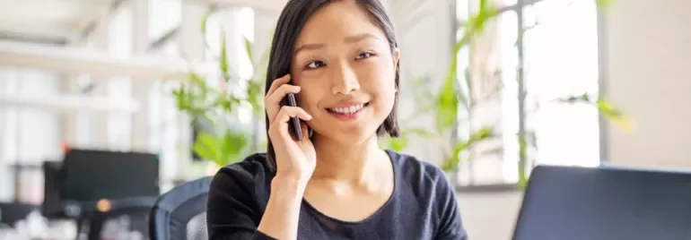Woman smiling while on a phone call in a modern office.