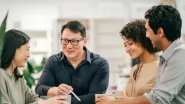 A gathering of people around a table, participating in a discussion and sharing insights in a group setting.