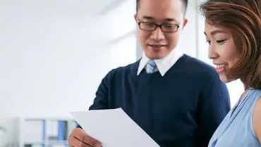 Two people reviewing a document together in a bright office.