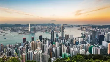 Skyline of a bustling city with skyscrapers and a vibrant harbor at sunset.