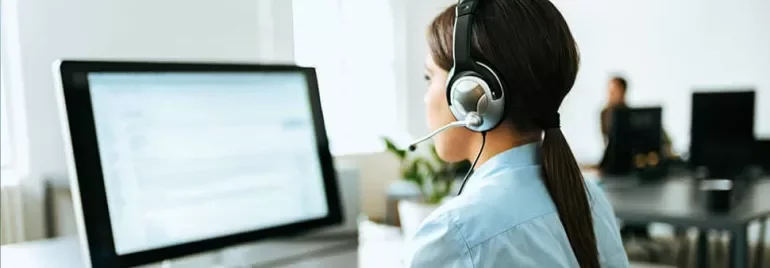 Woman with headset working at a computer in an office.