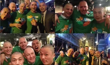 Group of friends smiling and posing at a night event, wearing matching green shirts.