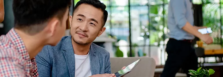 Two men having a conversation in a modern office with greenery.